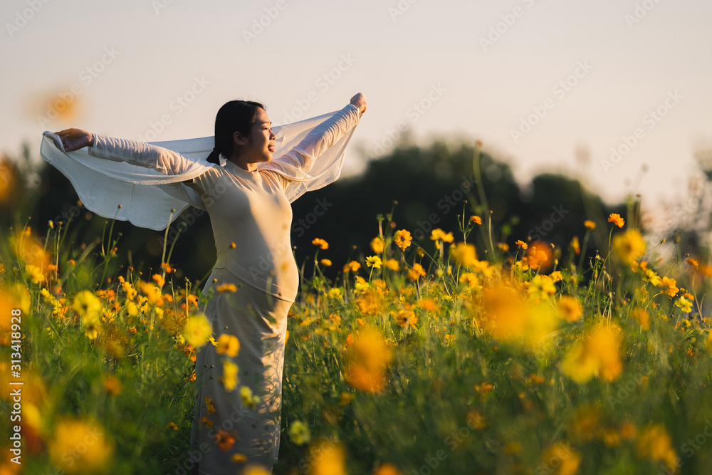 Pregnant woman is relaxing in the flower garden.