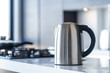 Silver metal electric kettle for boiling water and making tea on a table in the kitchen interior. Household kitchen appliances for makes hot drinks