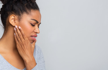 Young woman having acute toothache, holding her jaw