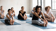 Diverse people with instructor doing Seated forward bend, practicing yoga