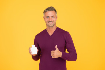 Product for sale. Happy guy give thumbs up to product. Handsome man presenting product. Product promotion. Bottle or container for advertising text, copy space