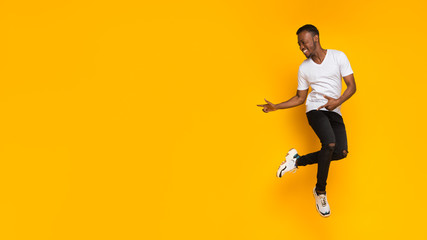 Poster - Guy Pointing Fingers Aside Having Fun Over Yellow Background, Panorama