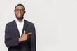© fizkes - African businessman isolated on grey pointing finger aside at copyspace