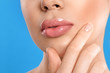 © New Africa - Young woman with beautiful full lips on light blue background, closeup
