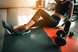 © Take Production - fitness ,workout, gym exercise ,lifestyle  and healthy concept. Side view of a woman sitting to relax after a workout with a whey protein and dumbbell and an apple placed beside in the gym at sunset.