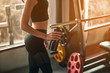 © Take Production - fitness ,workout, gym exercise ,lifestyle  and healthy concept. Close-up side view of a woman holding a protein shake bottle after a workout is done to relax and unwind at the indoor gym at sunset.