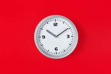 White wall clock with a yellow used hanging on the wall. Minimalist image of a wall clock on a red background with copy space