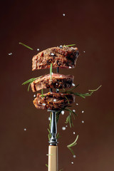 Grilled ribeye beef steak with rosemary on a brown background.