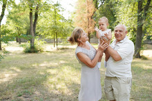 Grandparents And Baby Grandchild Walking In Nature Park, Copy Space