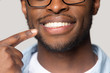 © fizkes - Closeup view african guy pointing finger to white toothy smile
