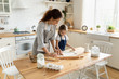 Young mother and little daughter preparing together pastry in kitchen