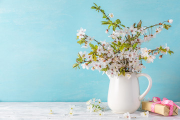 womans day or spring concept. still life with cherry blossom flowers and gift box on blue wooden background