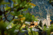 Hallstatt town center with a view on Evangelical Church through the tree branches, old townhouses, embankment of Hallstatter lake and Alps on the background, Salzkammergut, Austria.