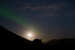  unbewohntes , dunkles, mystisches Haus vor Hügeln mit Polarlicht