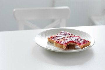 Bitten toast with jam on the table. Late for work did not have time to eat breakfast