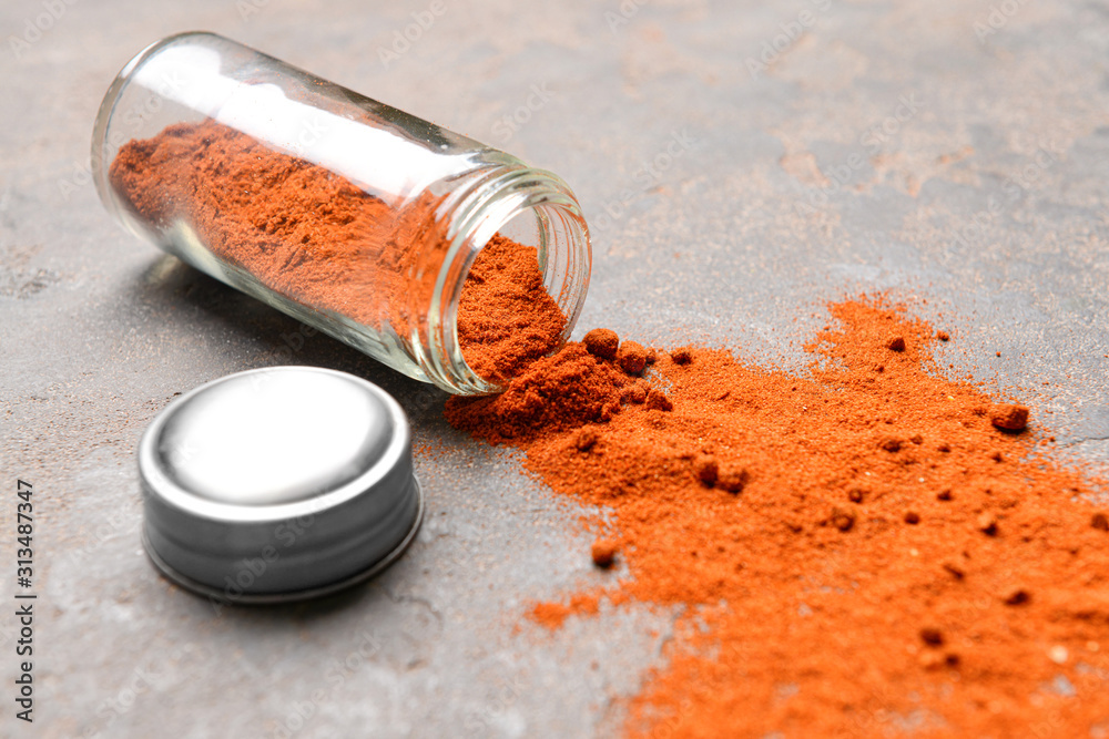 Jar with paprika powder on grunge background