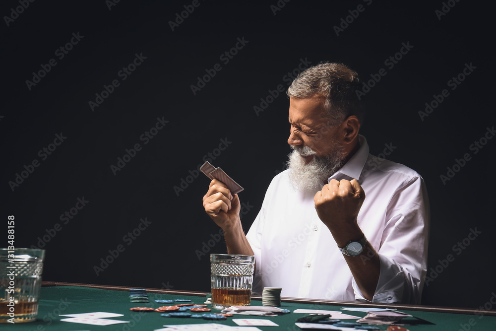 Happy mature businessman playing in casino