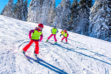 Group Of Kids Learning How To Ski On Slope In Mountains During Winter Vacation