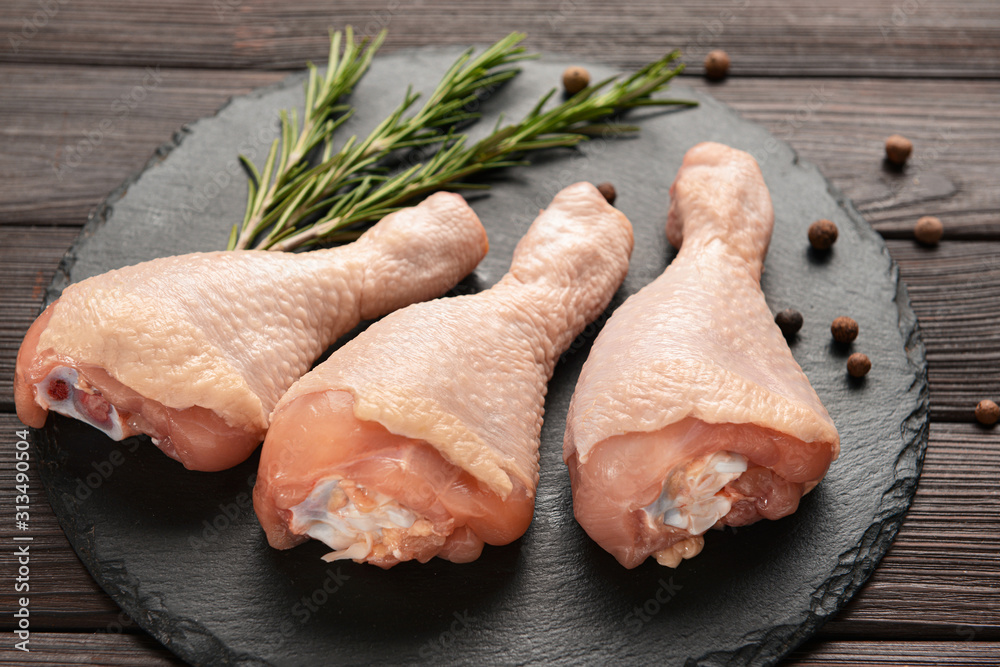 Raw chicken drumsticks on wooden background