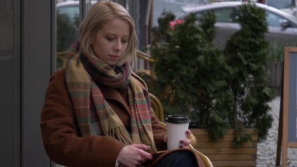 Sticker - woman drink a coffee cup and sitting on bench on the city street