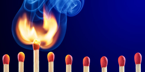 row of matchsticks with one bursting into flames - new idea concept