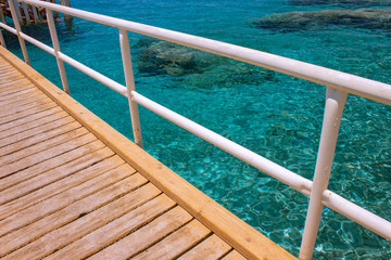 Wall Mural - summer time vacation season coral beach scenic view wooden bridge above Red sea background aquamarine water