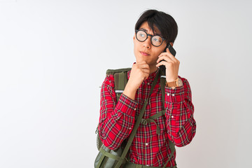 Wall Mural - Chinese hiker man wearing canteen talking on smartphone over isolated white background serious face thinking about question, very confused idea