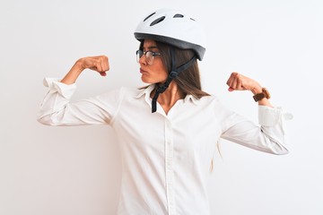 Wall Mural - Beautiful businesswoman wearing glasses and bike helmet over isolated white background showing arms muscles smiling proud. Fitness concept.