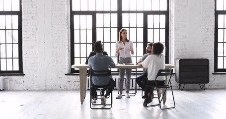 Wall Mural - Female leader speaking at team briefing in modern office space