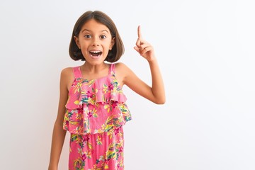 Sticker - Young beautiful child girl wearing pink floral dress standing over isolated white background pointing finger up with successful idea. Exited and happy. Number one.