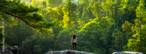Fotografía A young female hiker takes a break to enjoy a forest view.