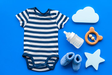 Wall Mural - Blue bodysuit for baby boy near children's accessories on blue background top-down