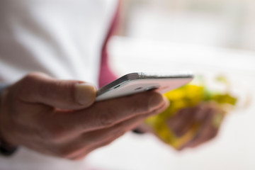 Wall Mural - man with mobile phone in one hand and in the other apple and measuring tape, concept of diet and health app