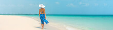 Luxury Beach Vacation Elegant Tourist Woman Walking Relaxing In Beachwear Hat On White Sand Caribbean Beach. Lady Tourist On Holiday Vacation Resort. Banner Panorama Landscape.