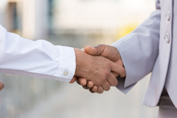 Wall Mural - Male and female professionals greeting each other in city. Closeup of business man and woman shaking hands outside. Dealing or trust concept