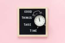 Good Things Take Time. Motivational Quote On Black Letter Board, Black Alarm Clock On Pink Background. Concept Inspirational Quote Of The Day. Greeting Card, Postcard