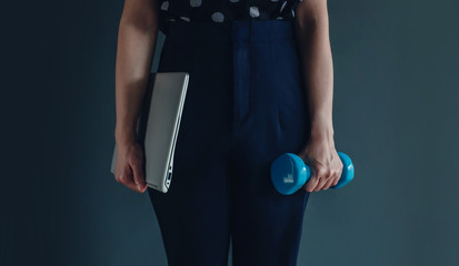 Wall Mural - Work Life Balance Concept, present by Business Working Woman holding a Laptop by right hand and another hand with a Dumbbell, Lifestyle of Modern People. Croped image with Copy Space