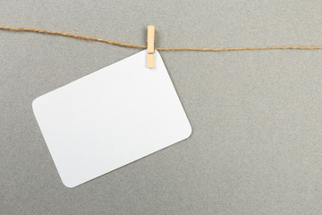 a piece of white paper attached to a rope clothespin on grey background  - Image