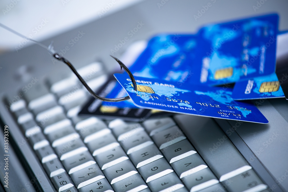 Credit card phishing. Piles of credit cards with a fish hook on computer keyboard. Credit card phishing scam with credit card in fishing hook