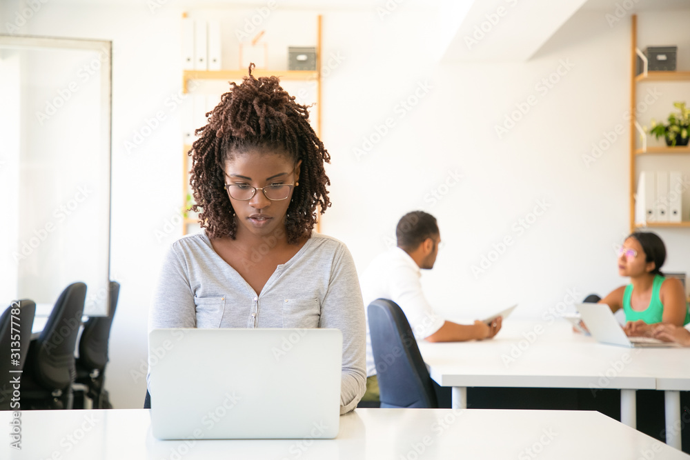 Front view of focused African American worker typing on laptop ...
