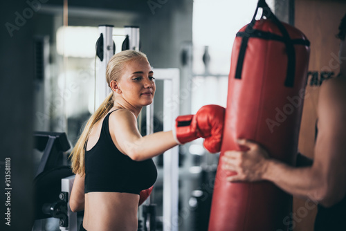 Fotografía An athletic woman boxer hitting the punching bag in the gym