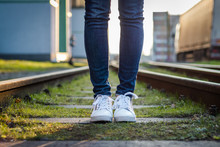 Woman Is Wearing White Sneakers And Standing At Rail Track