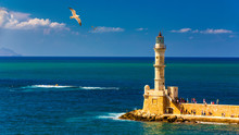 Venetian Harbour And Lighthouse In Old Harbour Of Chania With Seagulls Flying Over, Crete, Greece. Old Venetian Lighthouse In Chania, Greece. Lighthouse Of The Old Venetian Port In Chania, Greece.