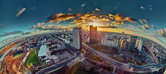 Wall Mural - Beautiful panoramic aerial drone view to the Сenter of modern Warsaw city with silhouettes of skyscrapers in in the rays of the setting winter January sun - amazing sunset, Poland