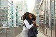 Happy office female friends meeting outside. Business women greeting each other in city and hugging. Old friends concept