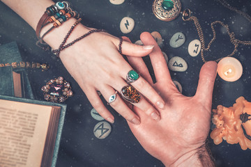 astrology and esotericism. a fortune teller reads a man's palm. on a black background lie runes, a c