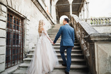 Beautiful Wedding Couple Climbing Up A Gorgeous Stairs Holding Hands And Looks To Each Other