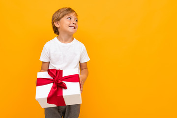 valentine's day concept. attractive boy with a gift box with a red ribbon on a bright yellow background with copy space