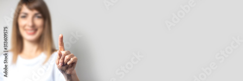 Fotografía Young woman touches or pushes a finger at something on a light background