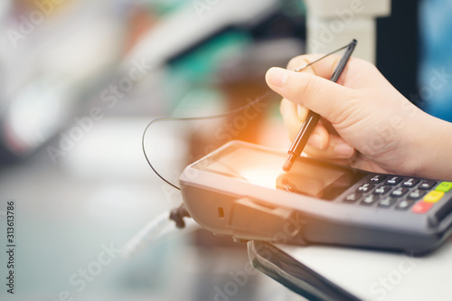 Fotomural Close-up of consumer's women hand signing on a touch screen of credit card sale
